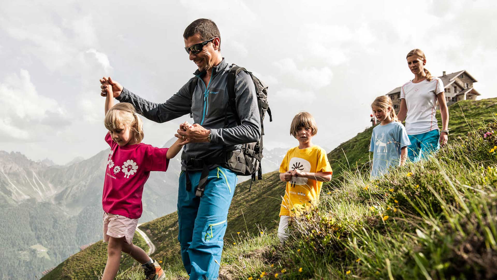 Eine Familie genießt den Sommerurlaub mit Familie in Tirol beim Wandern in den Bergen an einem sonnigen Tag.